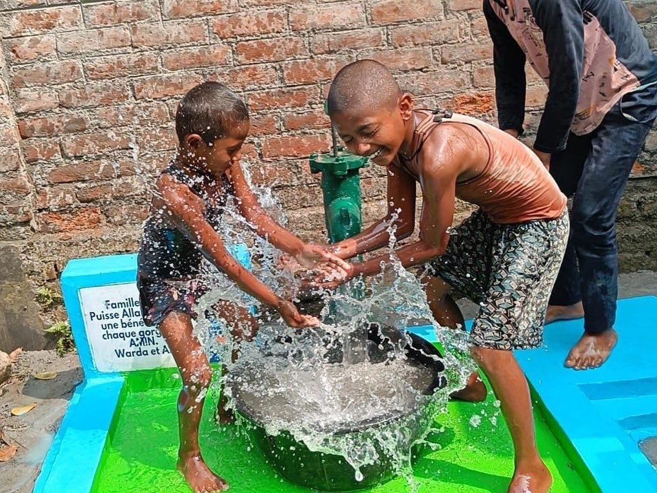 Children playing with water from a pump.