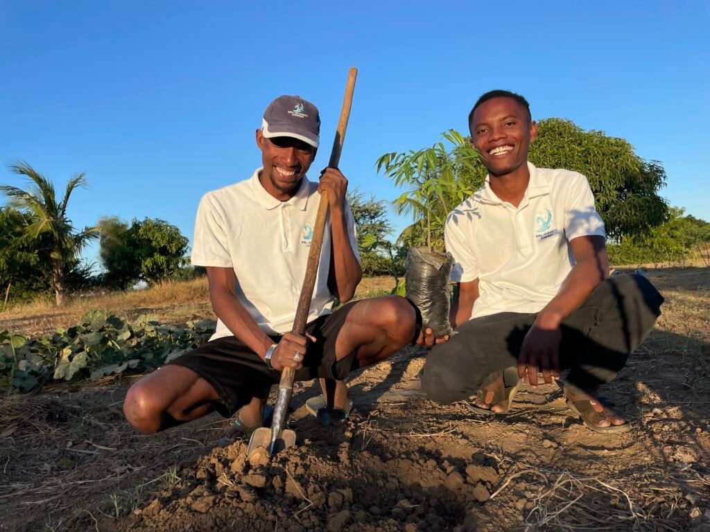 Two smiling people planting a tree.