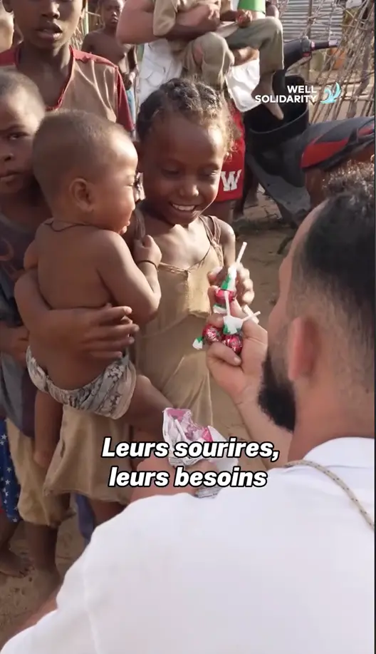 Man handing out sweets to smiling children.